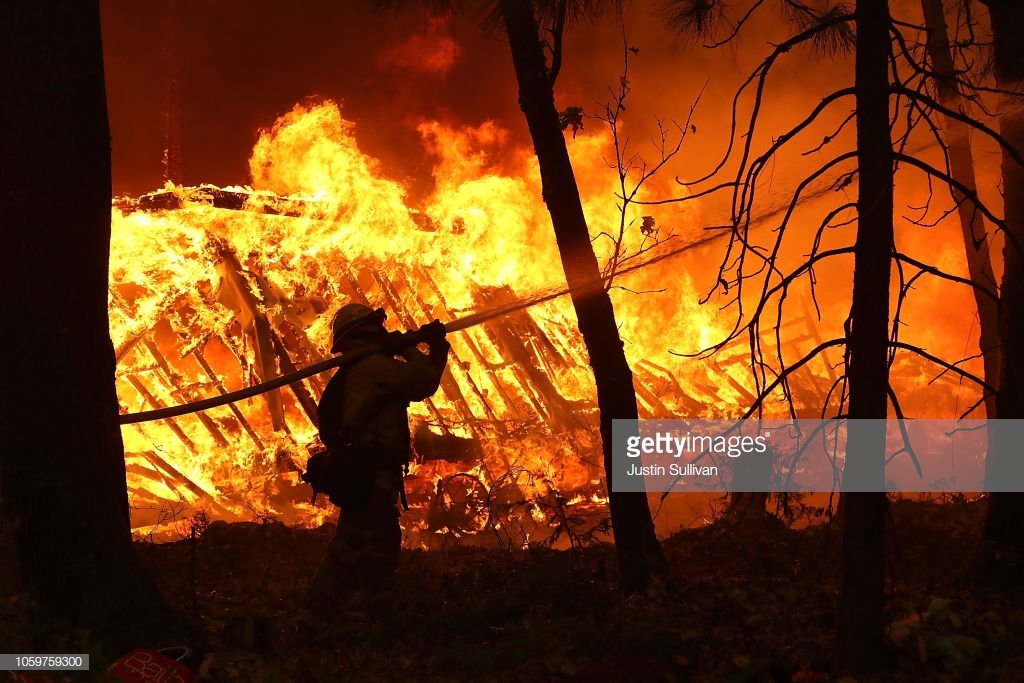 A Cal Fire firefighter sprays water on a home next to a burning home as the Camp Fire moves through the area on November 9, 2018 in Magalia, California. Getty Images/Justin Sullivan